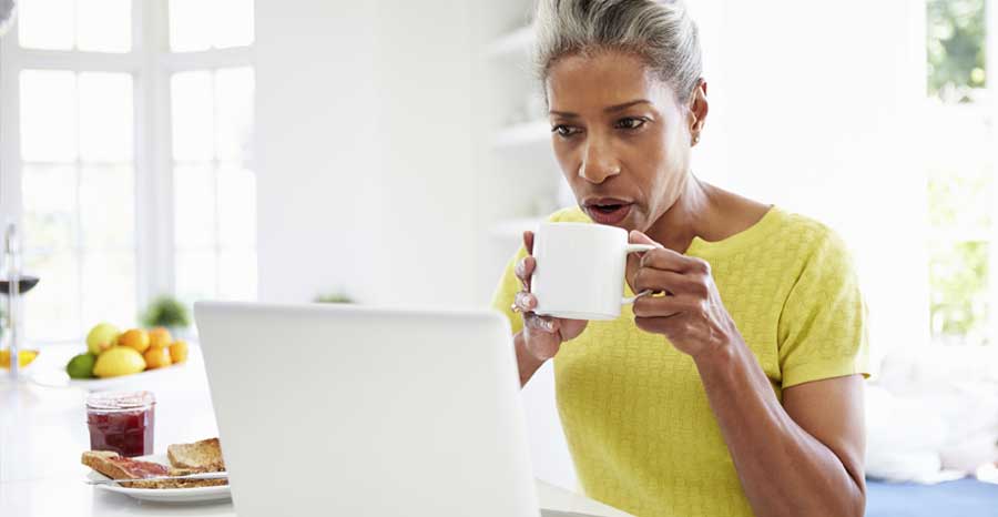 Women working on laptop with coffee in her hand