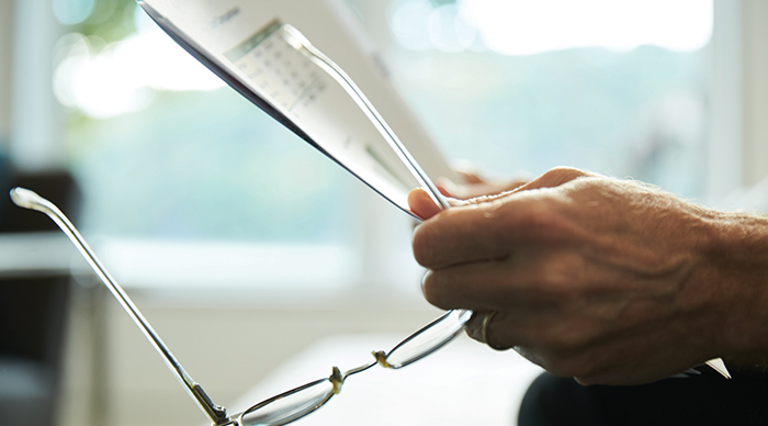 Man holding glasses and papers 