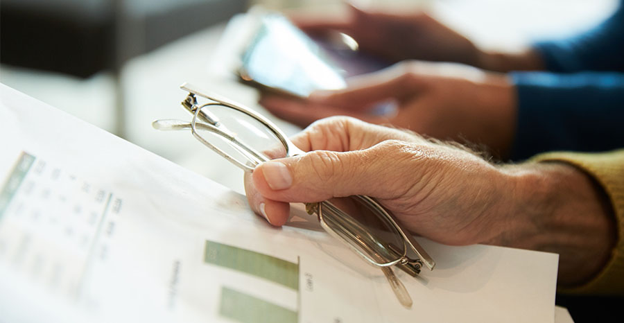 Man holding glasses and papers in hand
