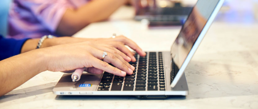 A pair of hands typing on a laptop